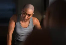 A bald character in a gray tank top leans forward in a dimly lit scene from Intergalactic: The Heretic Prophet.