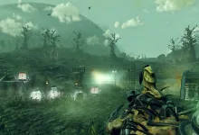 A first-person view across a misty site with dead trees and illuminated structures, with an alien tool visible in the foreground.