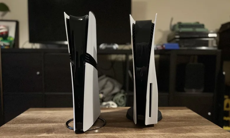 Two white PlayStation 5 consoles stand upright on a wooden table.