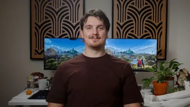 A man sits in front of a monitor displaying RuneScape scenery.