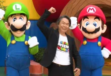 Shigeru Miyamoto poses between Mario and Luigi at Super Nintendo World.