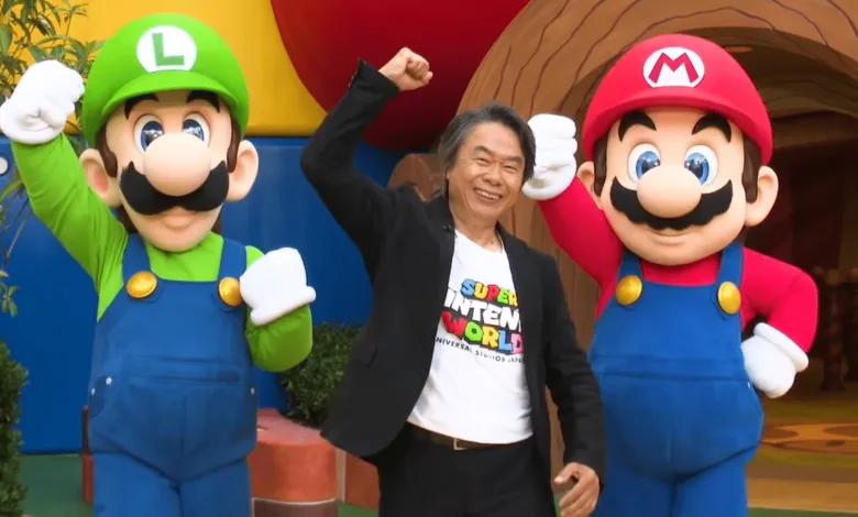 Shigeru Miyamoto poses between Mario and Luigi at Super Nintendo World.