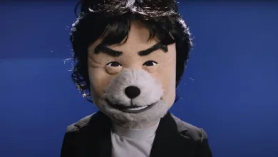Shigeru Miyamoto wearing a gray furry muzzle against a blue backdrop.