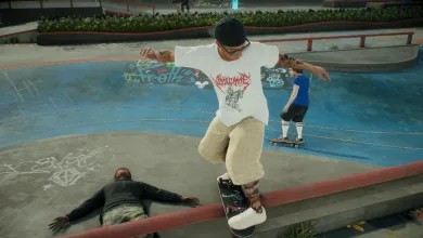 A skater in a white shirt and tan pants balances on a skateboard while grinding a low rail at a skatepark, with another character on the ground nearby.