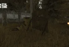 An overgrown area beside a concrete fence, with a barrel, debris, and a small orange glow.