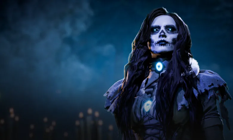 A dark-haired contestant with skull-like makeup and a glowing blue pendant stands against a smoky blue background.