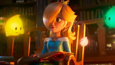 Rosalina sits in a library holding an open book, with yellow and green Lumas nearby.