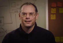 Tim Sweeney speaking in an office in front of a whiteboard and notes.