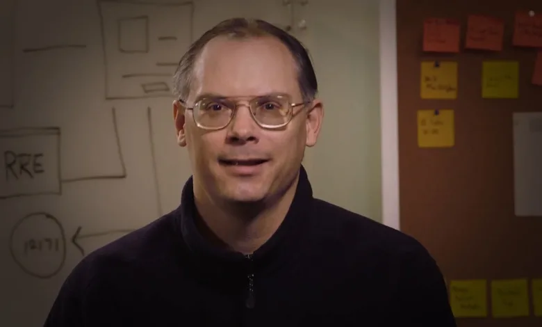 Tim Sweeney speaking in an office in front of a whiteboard and notes.