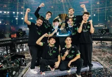 LOUD players pose around the VALORANT Champions trophy in an arena.