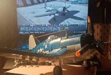 A blue Corsair model sits in front of a monitor showing War Thunder.