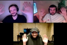 Three men wearing headsets raise their hands during a video call.